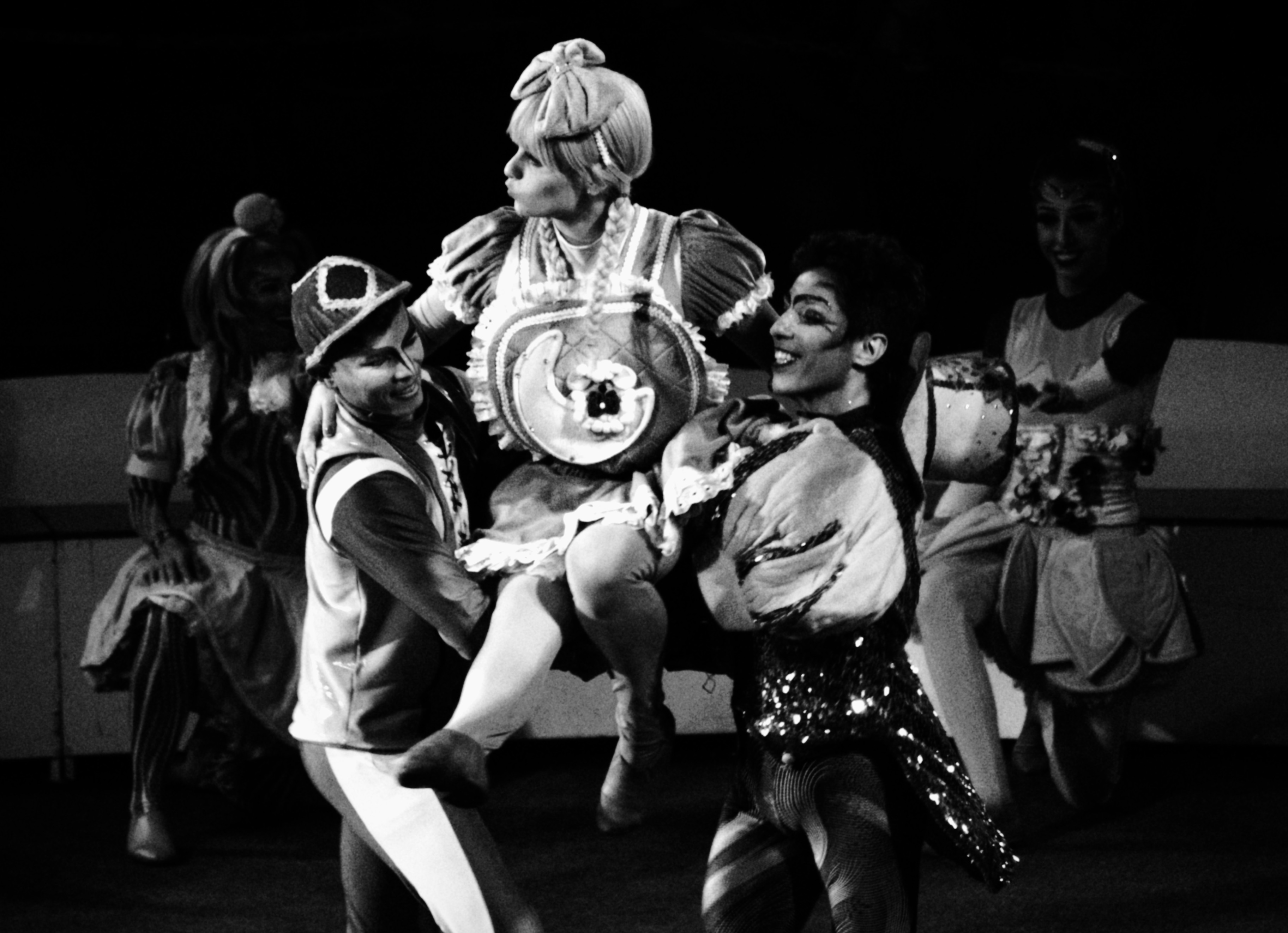 Circus performers in elaborate costumes, one lifted by two others