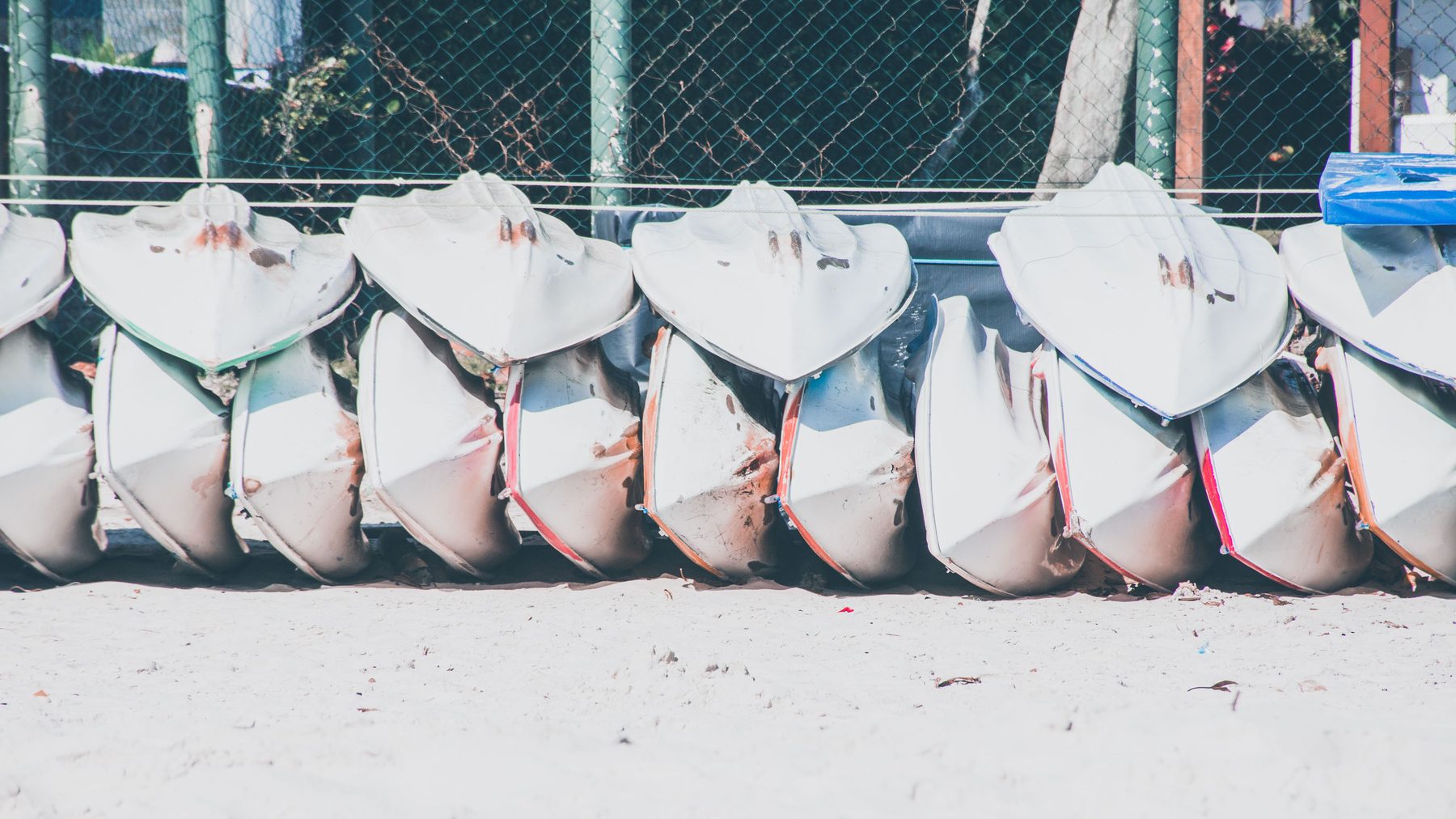 Row of stored fishing canoes on sand
