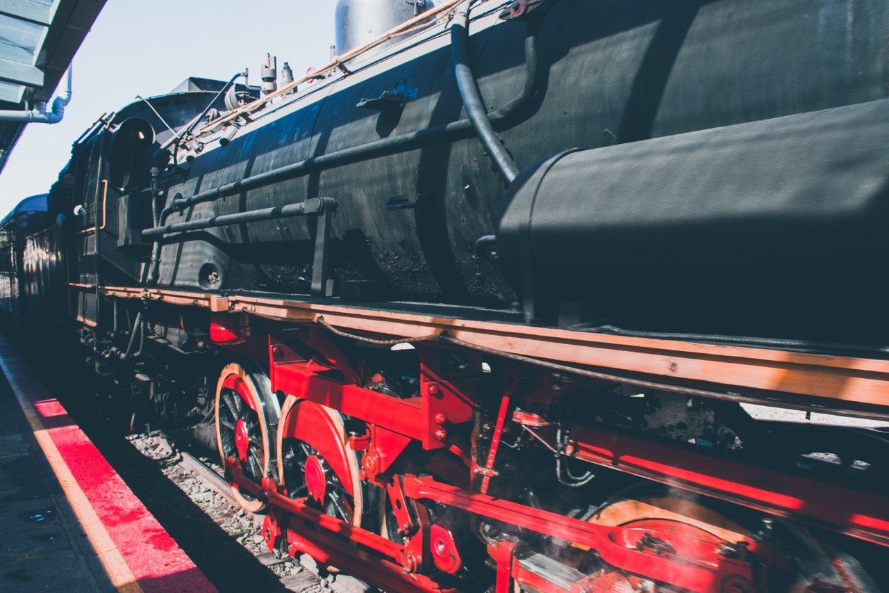 Black steam locomotive with red wheels at a station
